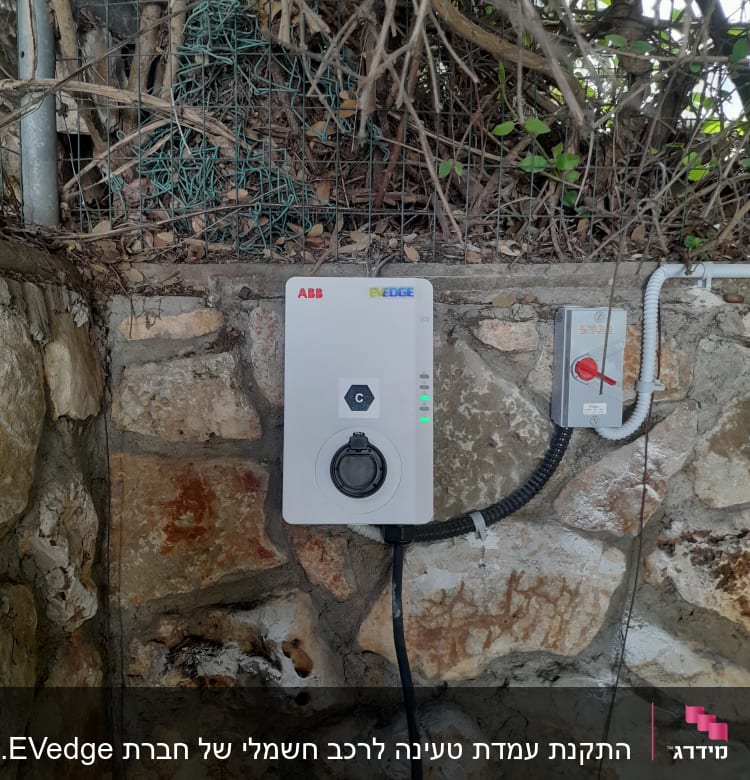 מטען חשמלי מותקן על קיר אבן עם כבלים